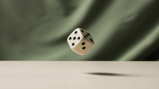 A single die caught mid-air above a cream surface