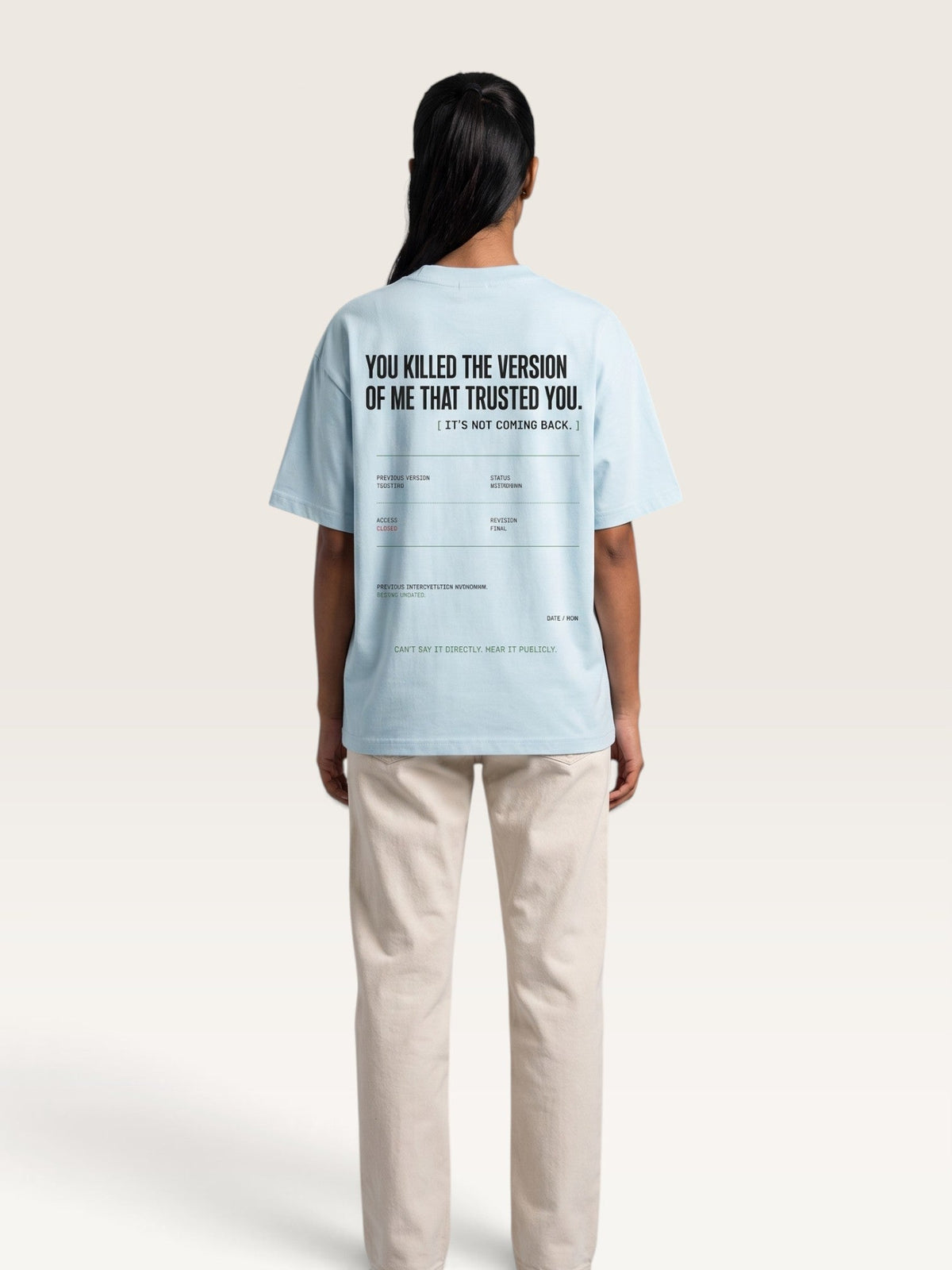 Sky Blue - A model shown from the back wearing a light blue graphic t-shirt and beige trousers against a solid off-white background.