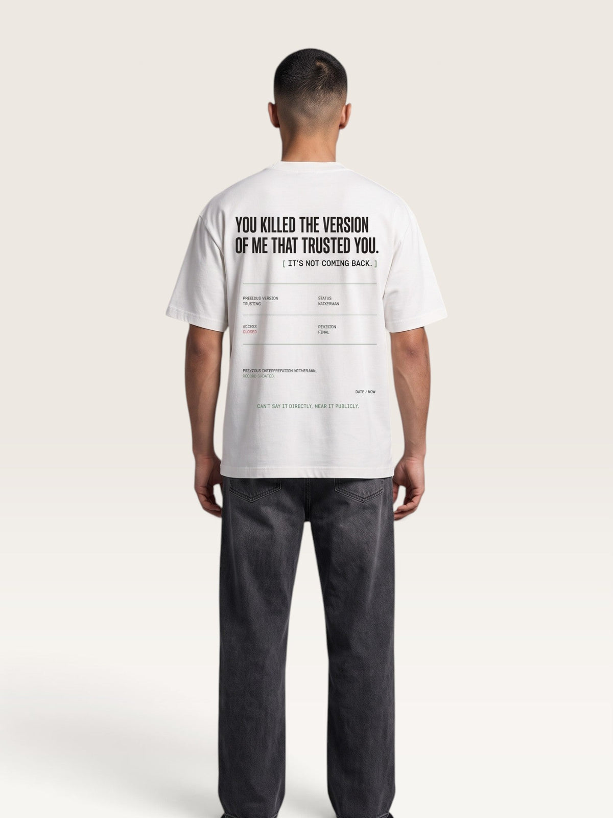 White - A man viewed from behind wearing a white t-shirt with black printed text on the back and dark gray jeans, standing against a light beige studio background.