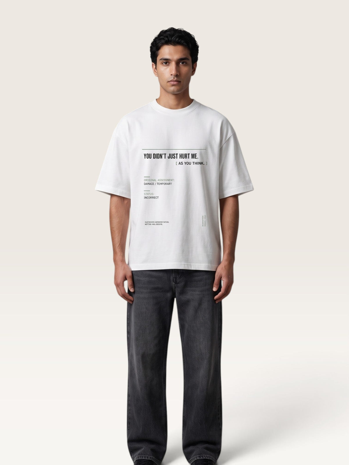 White - A man wearing a white oversized graphic T-shirt with black text and dark gray jeans, standing against a plain light beige studio background.