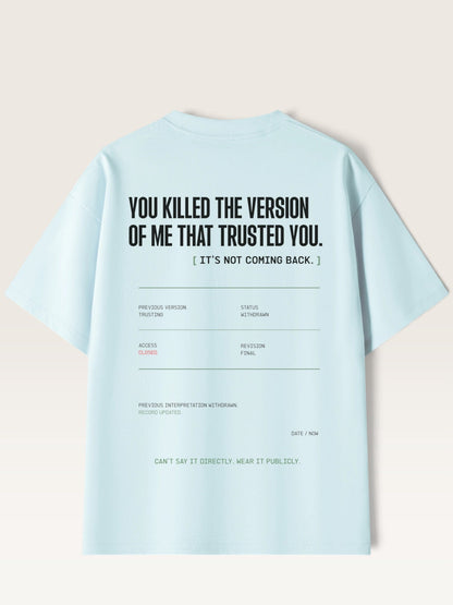 Sky Blue - A light blue short-sleeve t-shirt shown from the back, featuring a humorous text graphic in black and small gray and green details on a light beige background.