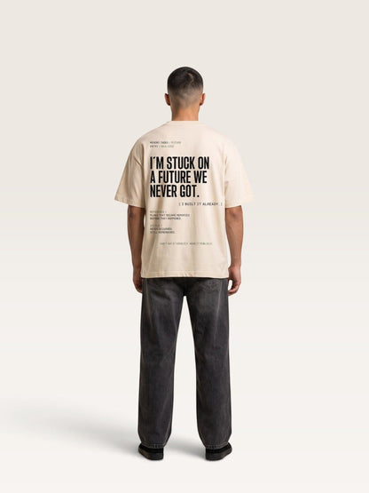 Mild Apricot WEARCAPTION beige heavyweight cotton oversized t-shirt with black graphic text on the back, worn by a man.