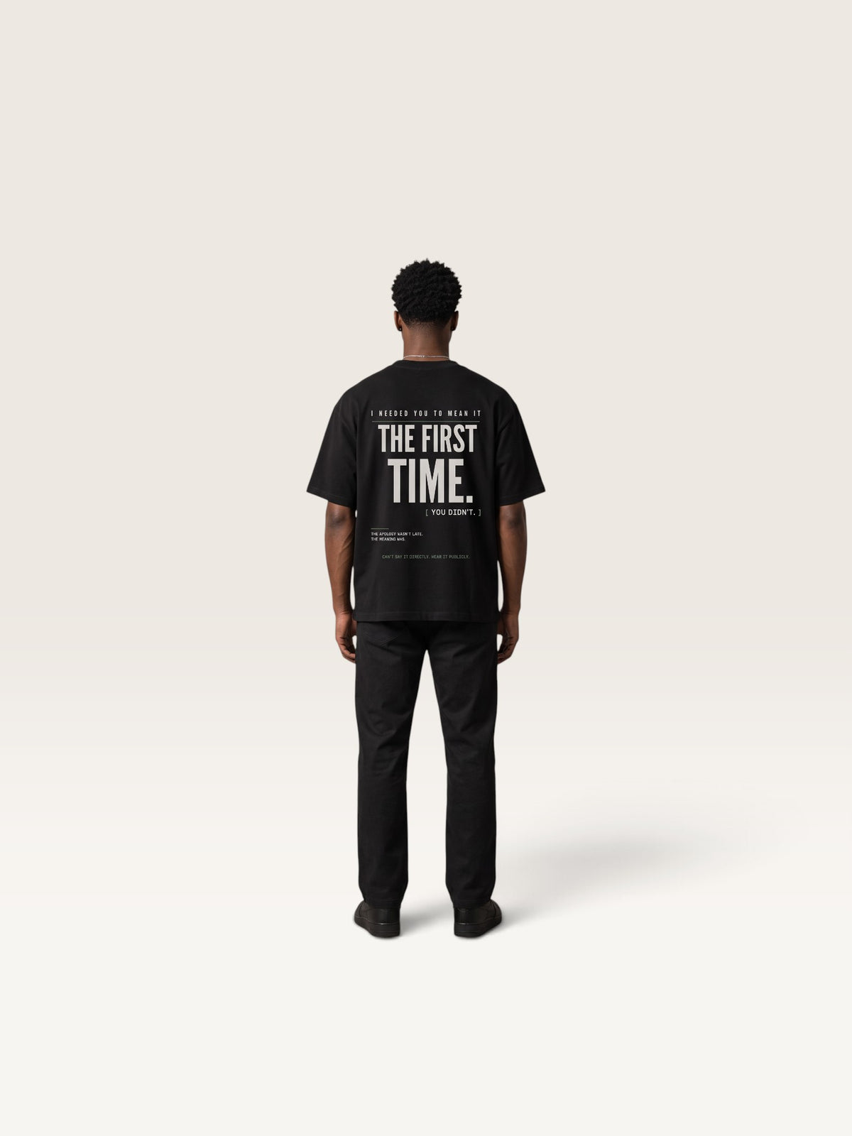 Black WEARCAPTION black heavyweight cotton oversized t-shirt with white graphic text on back, worn by a man in a studio.