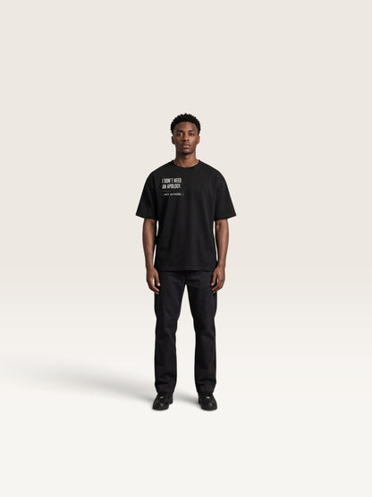 Black WEARCAPTION model wearing a black heavyweight cotton oversized t-shirt with white I DON'T NEED AN APOLOGY text print