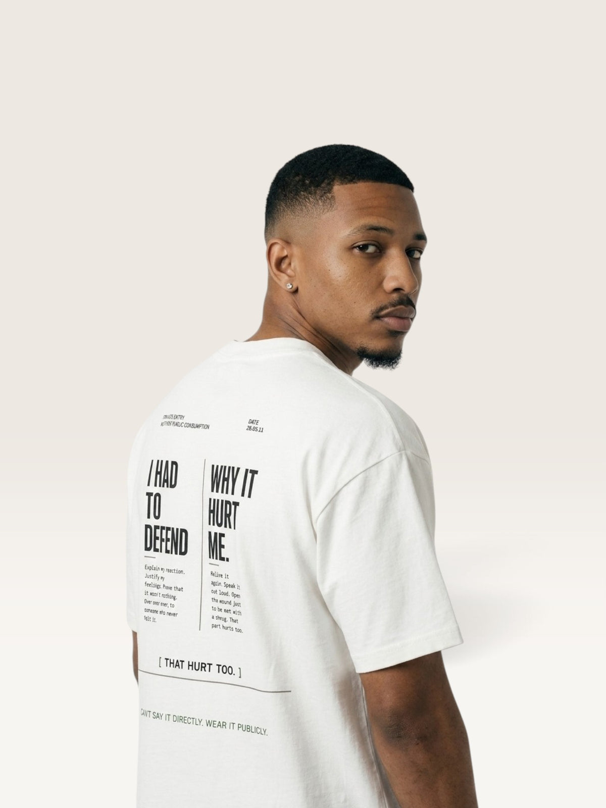 White WEARCAPTION heavyweight white cotton t-shirt with black typographic back print worn by a man looking over his shoulder