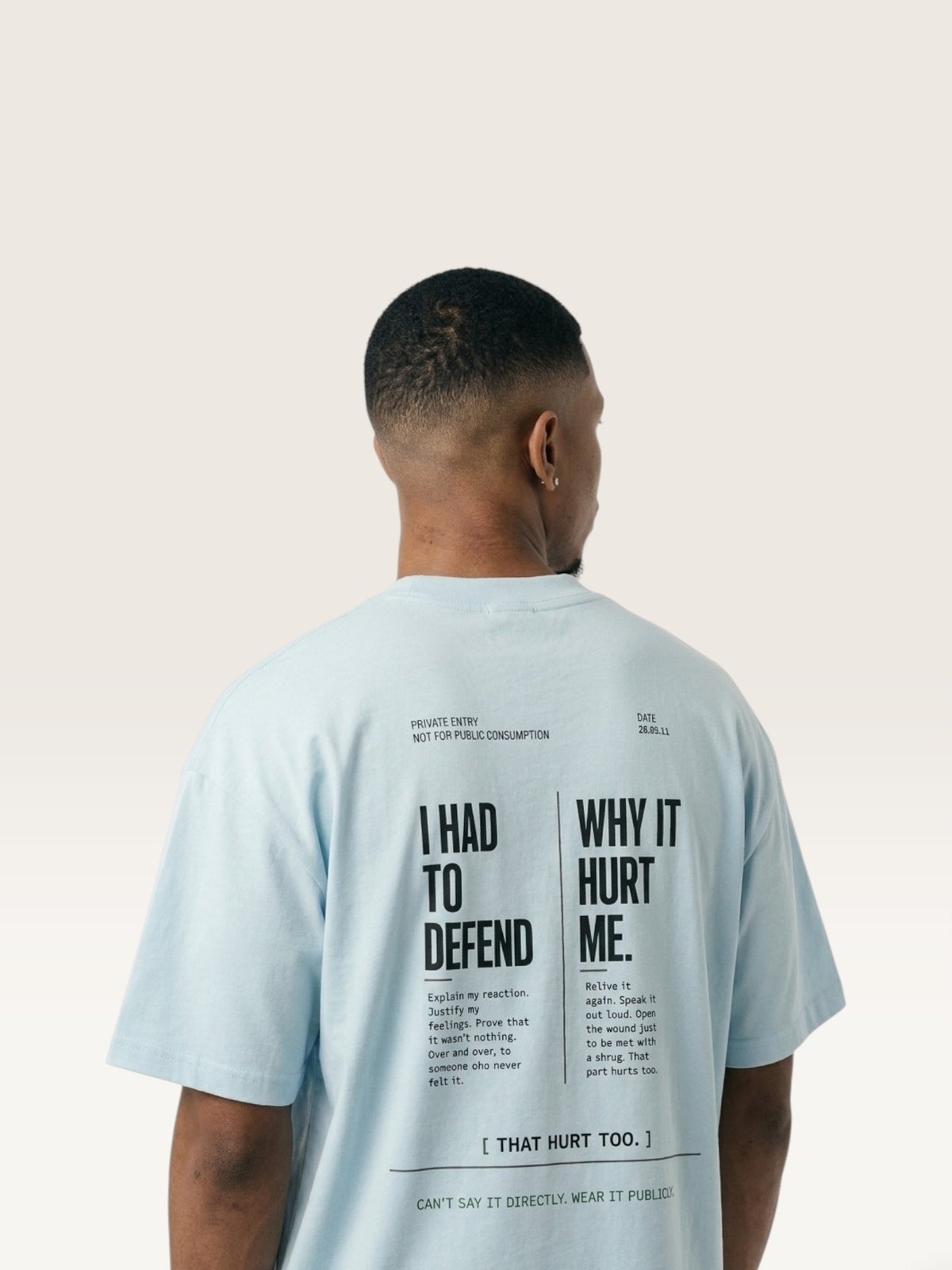 Sky Blue WEARCAPTION light blue heavyweight cotton t-shirt with black text graphic on the back worn by a man from behind