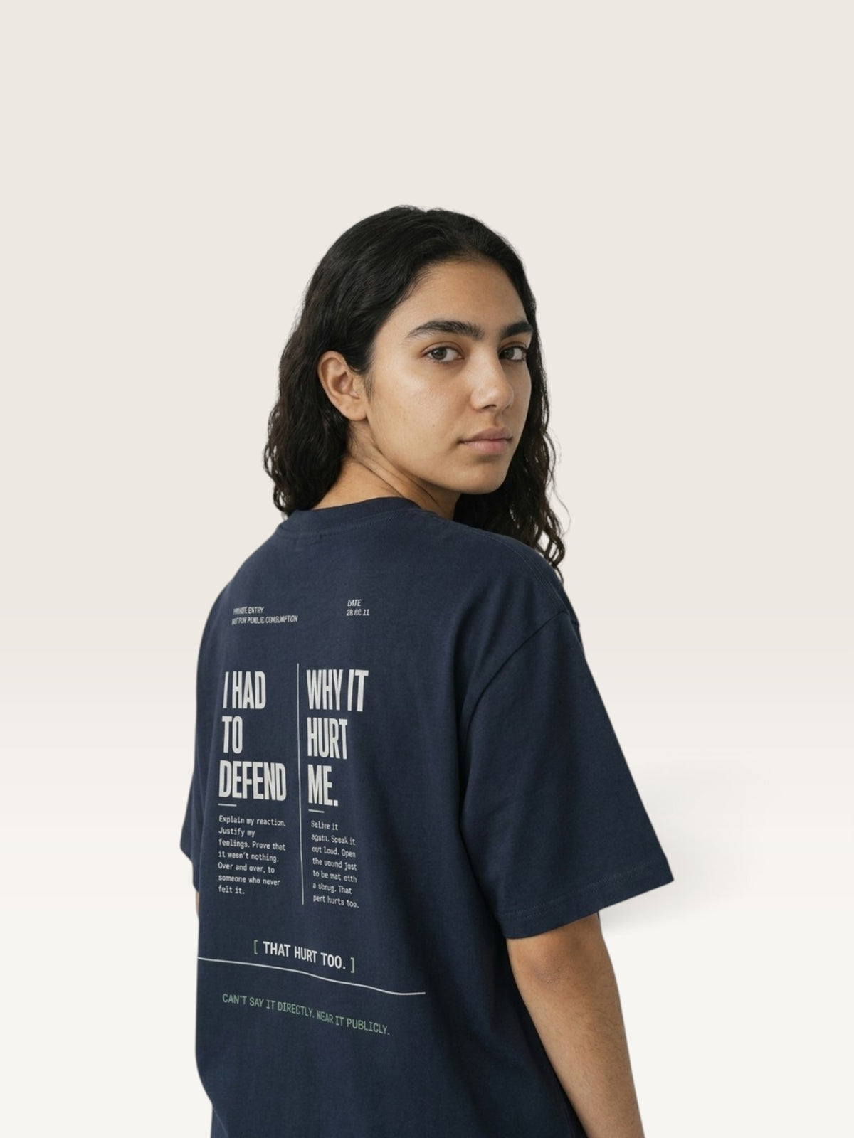 Navy Blue WEARCAPTION navy heavyweight cotton t-shirt with white back graphic text, worn by a woman looking over her shoulder.