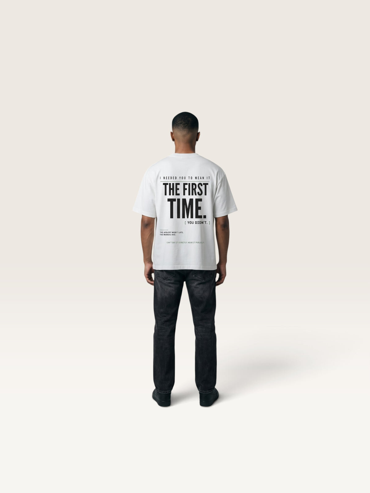 White WEARCAPTION white heavyweight cotton oversized t-shirt with black graphic text on the back, worn by a man.
