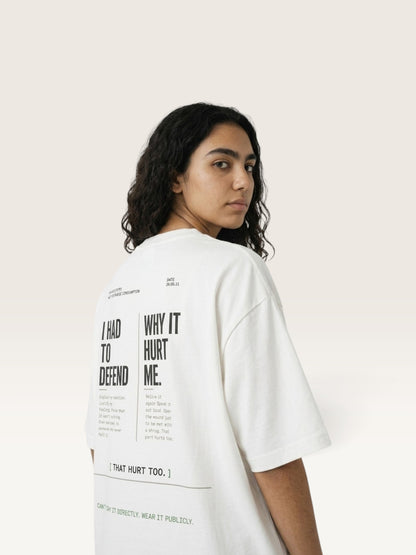 White WEARCAPTION oversized white heavyweight cotton t-shirt with black typographic back print worn by a woman looking back