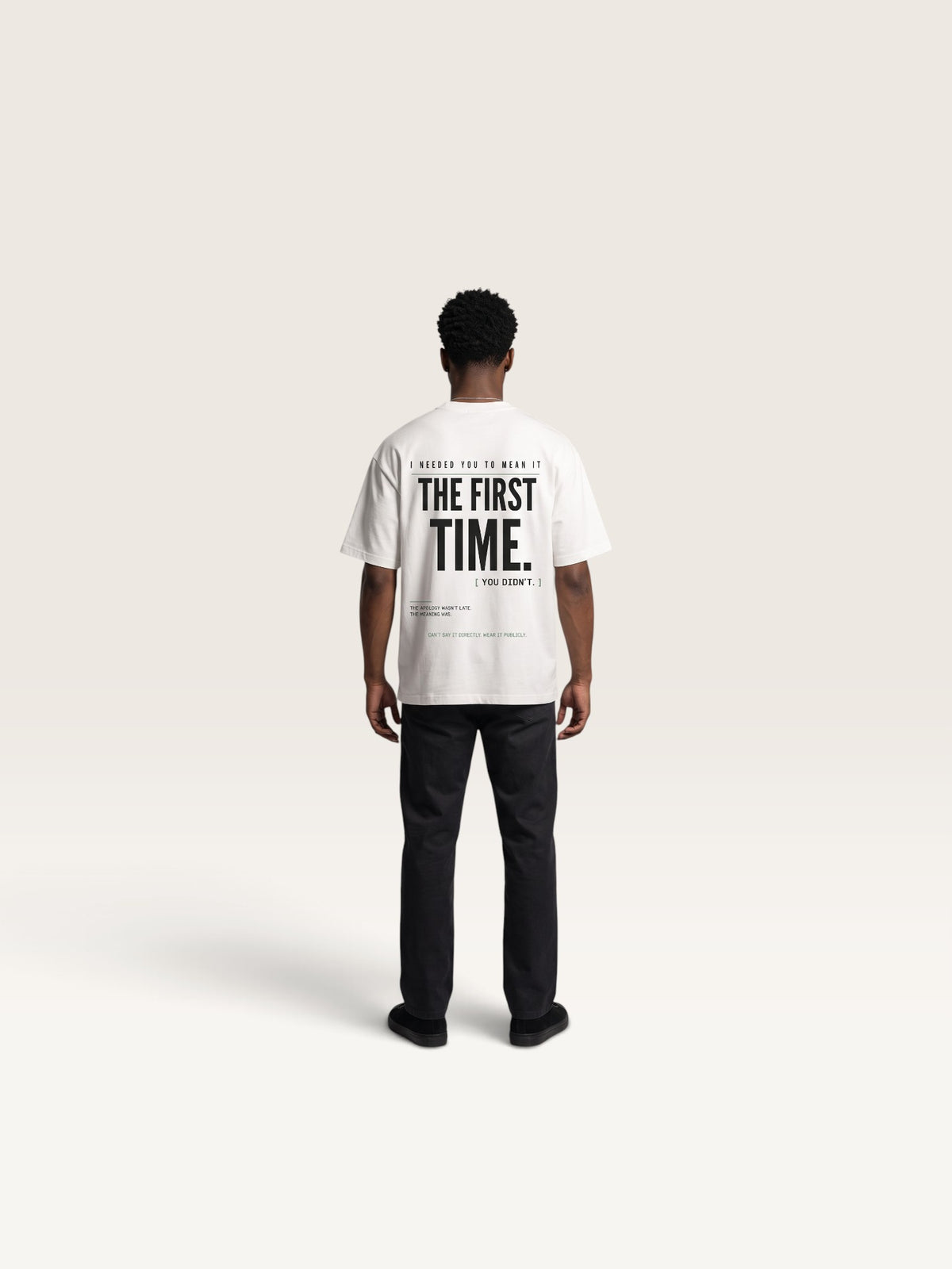 White WEARCAPTION white heavyweight cotton oversized t-shirt with bold black typography on the back, worn by a man.